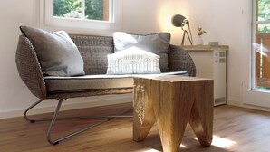 Un canapé en osier avec des coussins, une table basse en bois et une lampe posée sur une étagère.
