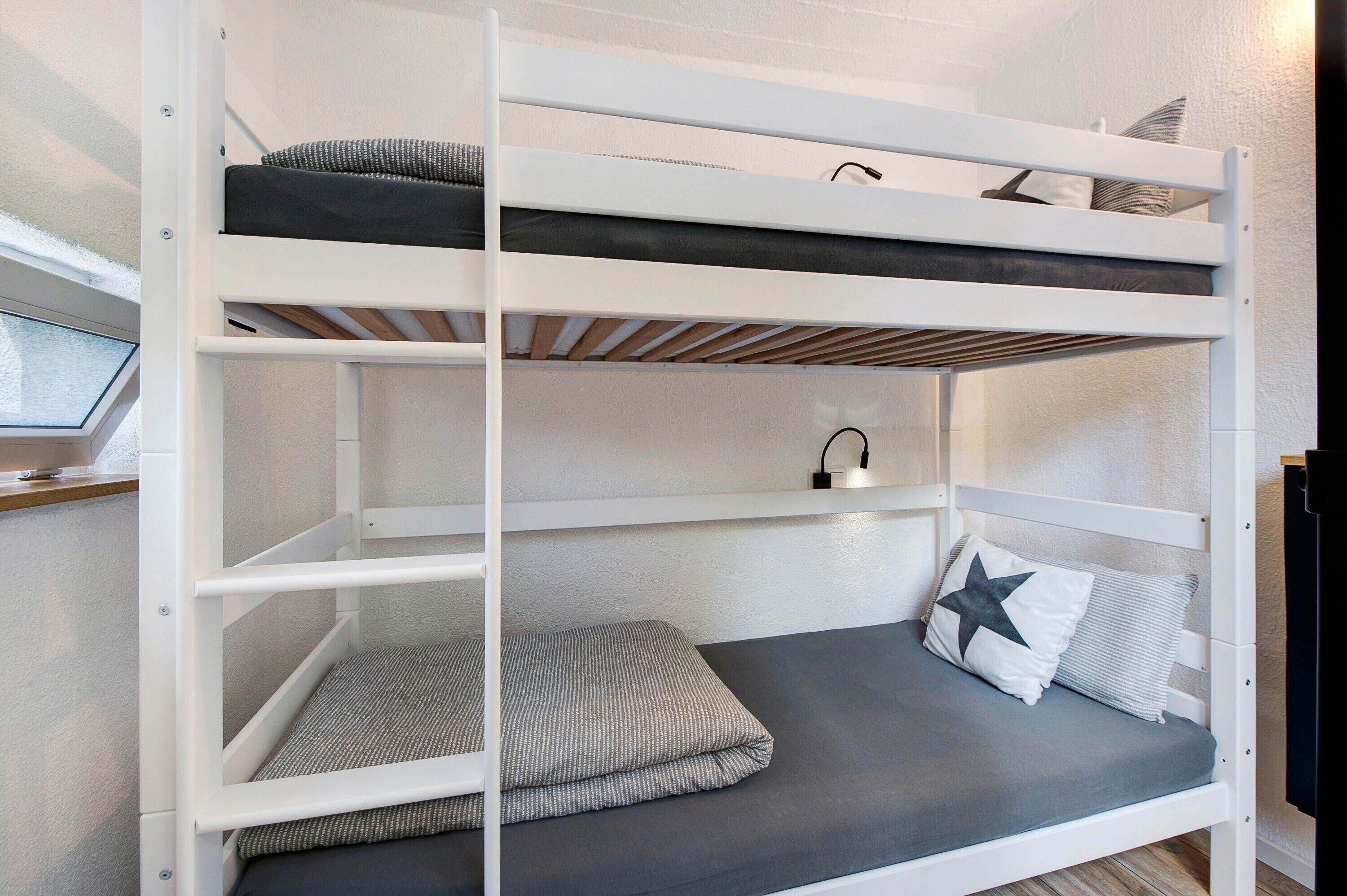 Una cama individual superpuesta con escritorio y lámpara.
