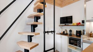 Una cucina moderna con forno a microonde integrato, macchina del caffè e televisore su uno scaffale.