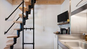 Una cucina moderna con piano cottura integrato, lavello in acciaio inossidabile e una scala in legno.