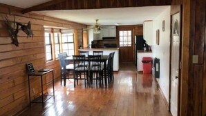 A spacious room with wooden walls and a dining area.