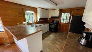 A compact kitchen with wooden walls, a central island, a stove, and a sink.