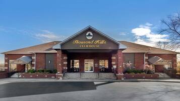 Un edificio de ladrillo con un letrero que dice 'Thousand Hills Clubhouse' y entradas para una tienda de golf y bienes raíces.