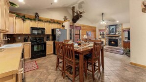 A spacious kitchen with wooden cabinets, a dining area with a table set for four, and a fireplace.