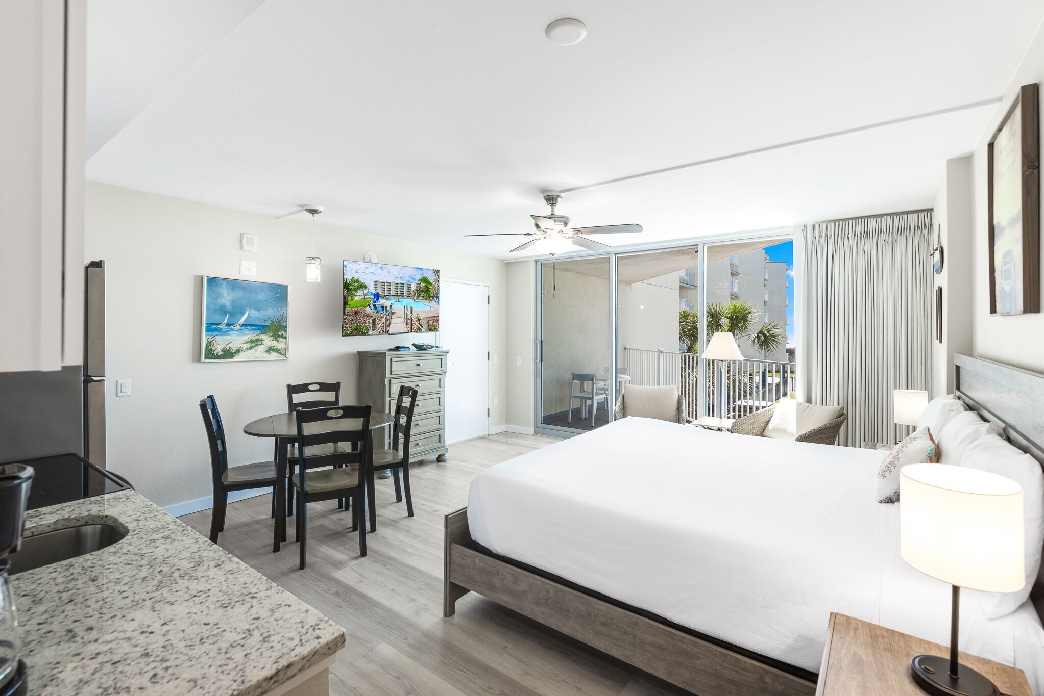 Hotelkamer met een bed, bureau, stoel, eettafel en balkon met uitzicht.