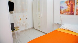 Un dormitorio con cama, armario, escritorio con silla, televisor y un cuadro en la pared.