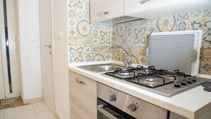 Una cocina con estufa a gas, lavamanos y un salpicadero decorativo.
