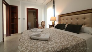 A hotel room with a large bed, a wooden wardrobe, a chair, and a nightstand with a lamp. - Villa del Fresno with pool and parking (Chiclana)
