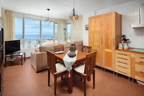 Un soggiorno moderno con divano, tavolo da pranzo e sedie, televisione e vista sul mare.