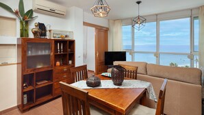 Uma sala de jantar com uma mesa de madeira, cadeiras, uma televisão e um sofá.