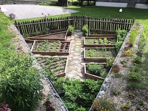A garden with raised beds and a wooden fence. - Chalet 'Kasern' with Mountain View, Private Terrace and Wi-Fi (Gais)