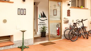 Entrada de un edificio con puerta de cristal, extintor y bicicletas estacionadas afuera.