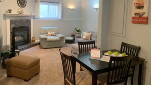 A living room with a fireplace, a dining table with chairs, a sofa, and a coffee table. - Cozy Basement Suite close to Downtown (Edmonton)