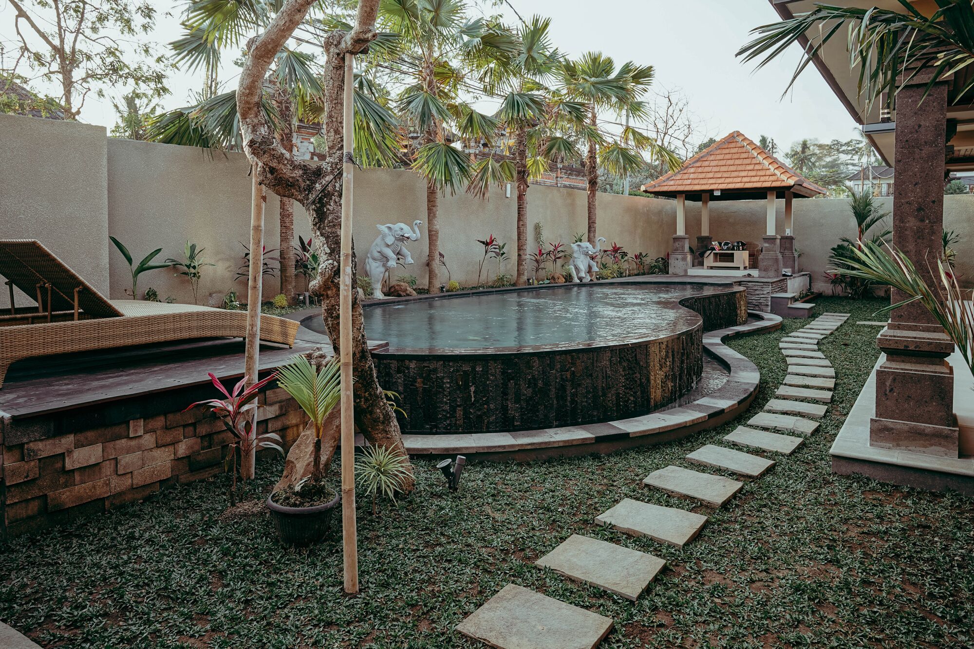 A landscaped garden with a circular water feature, stone steps, and a gazebo.