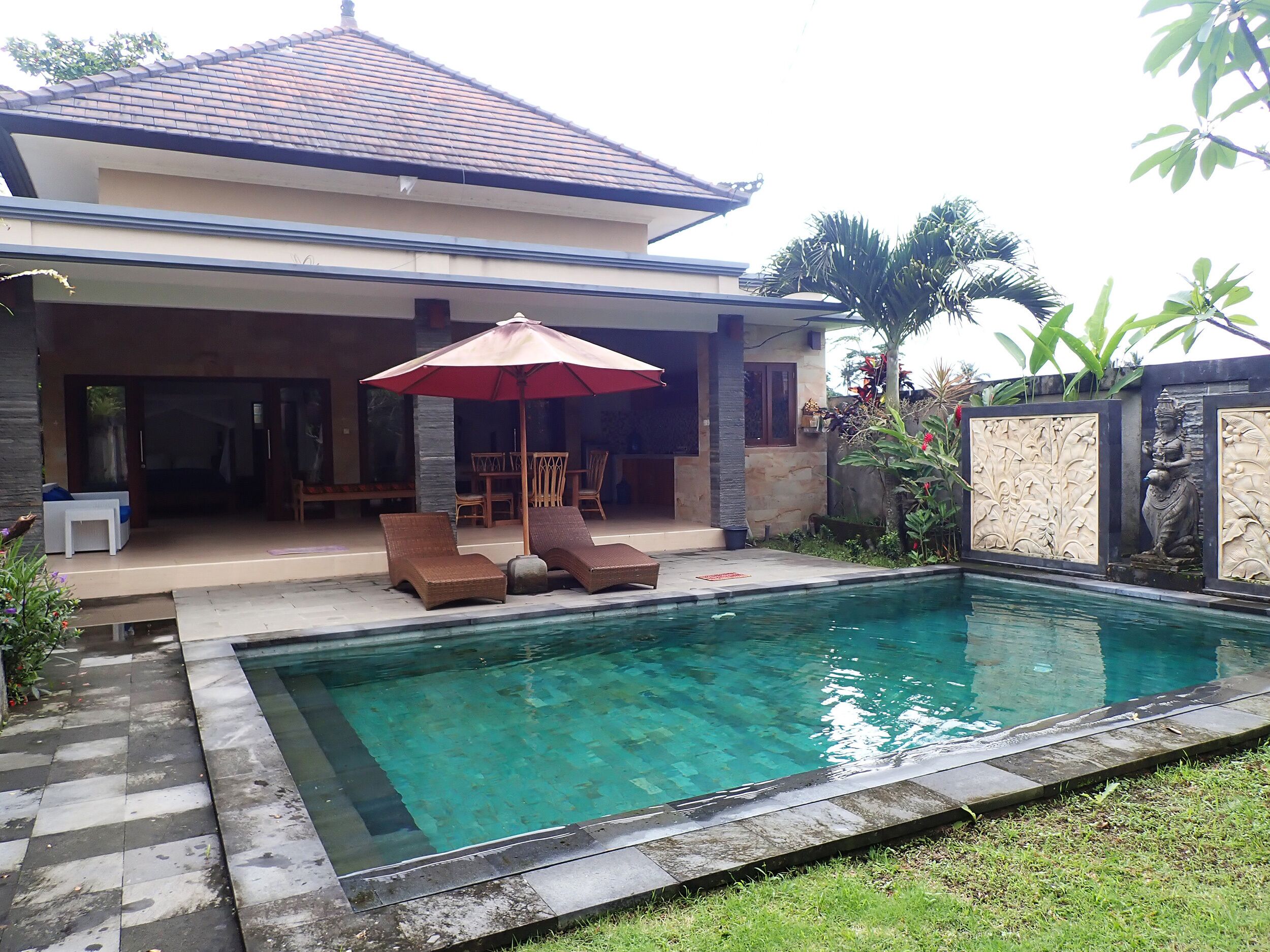 Uma casa moderna com piscina, espreguiçadeiras e área de jantar externa.