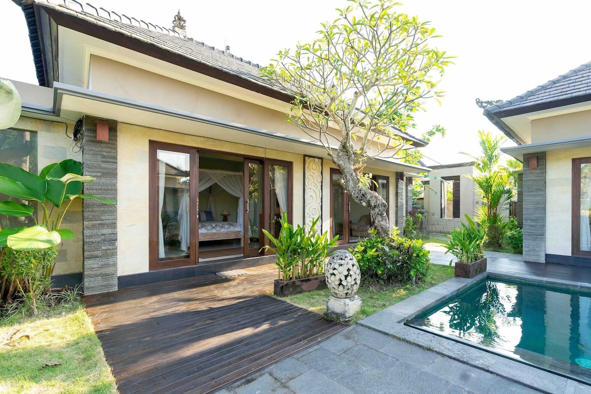 Et moderne hus med pool, store vinduer og en velplejet have.