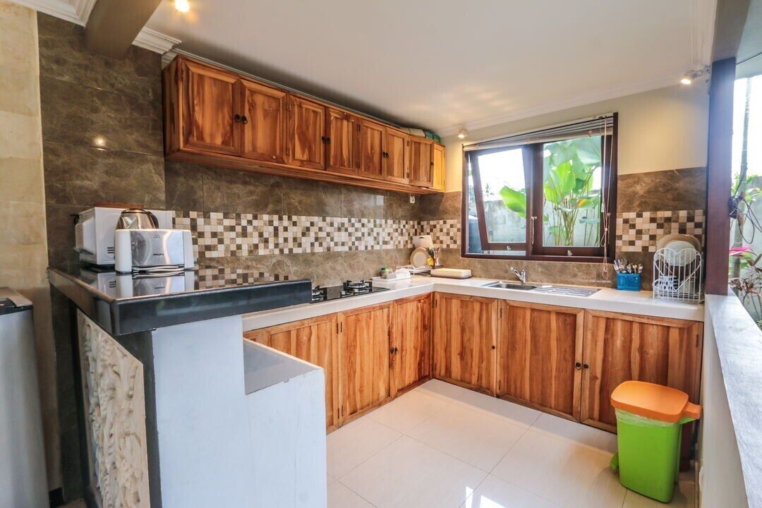 A modern kitchen with wooden cabinets, a tiled backsplash, and a window with plants.