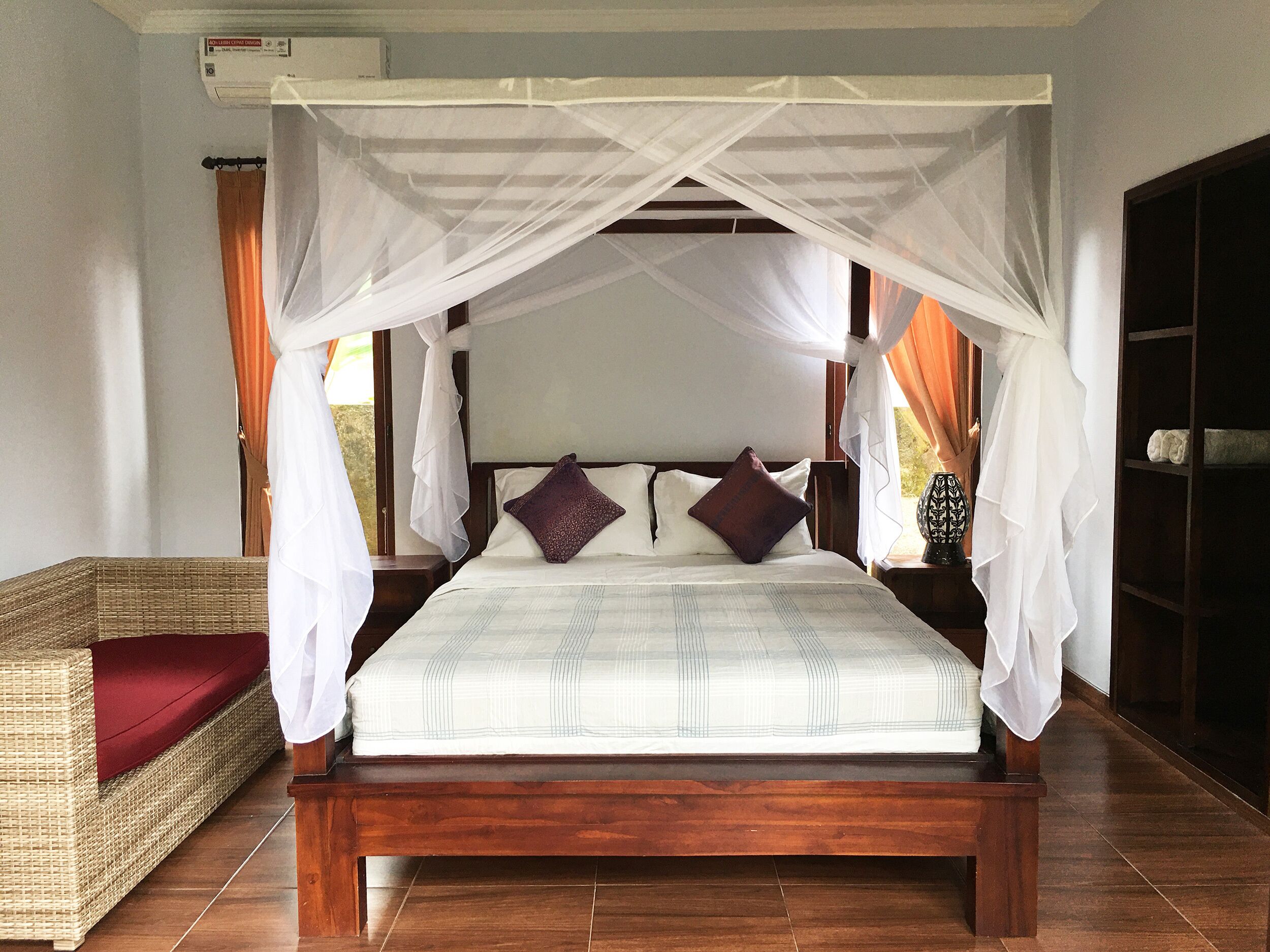 A bed with a canopy, a wicker sofa, and a tiled floor.