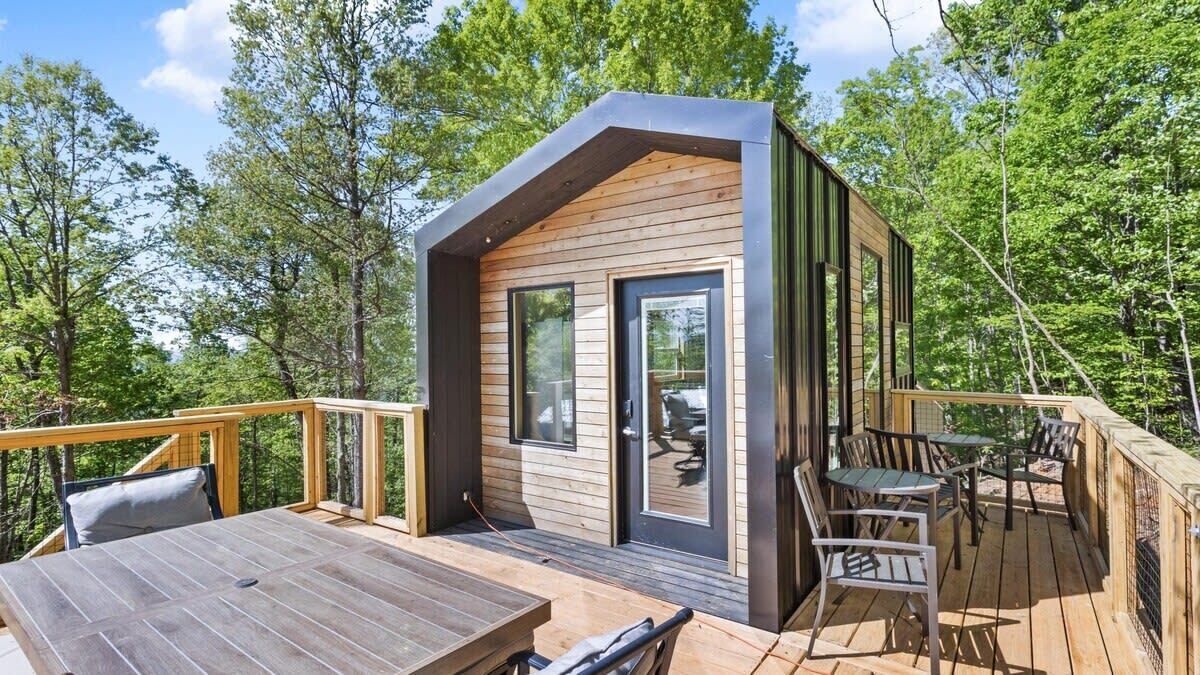 A modern cabin with a deck, large windows, and a door.