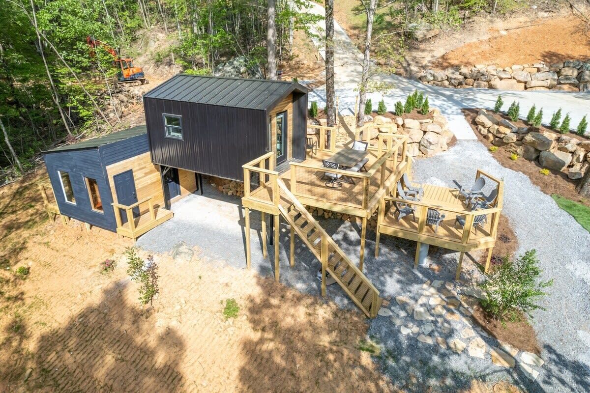 A cabin with a deck, outdoor seating, and a small building.
