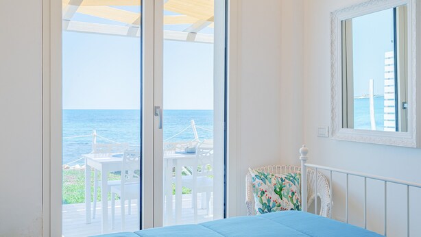 A bedroom with a bed, a window, and a view of the sea.