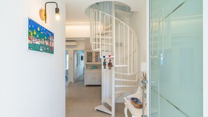 A spiral staircase leading to a second floor, a kitchen area with cabinets, and a wall-mounted artwork.