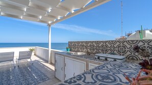 A patio with a view of the sea, a tiled backsplash, and a small sink.
