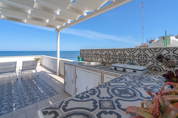 Une terrasse avec vue sur la mer, un mur recouvert de carreaux et un petit évier.