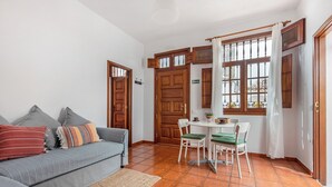 Un salon avec un canapé, une table à manger avec des chaises, une fenêtre avec des rideaux et une porte.