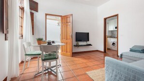 Un espace de vie compact comprenant un coin repas, un téléviseur, un lave-linge et une kitchenette.