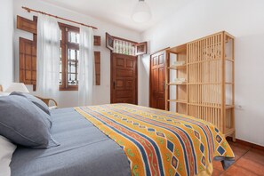 Une chambre à coucher avec un lit, une armoire en bois et une fenêtre avec des rideaux.