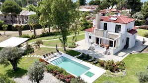 Una villa moderna con piscina, mobiliario de exterior y vistas al mar.
