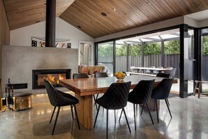Un comedor moderno con una gran mesa de madera, sillas tapizadas en negro y una chimenea.