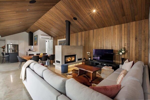 Una sala moderna con chimenea, un sofá, una mesa de centro y un televisor.