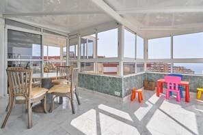 Een ruim balkon met een eethoek, stoelen en uitzicht op zee.