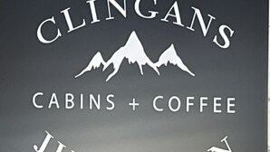 A sign for 'CLINGANS CABINS + COFFEE JUNCTION' with a mountain silhouette.