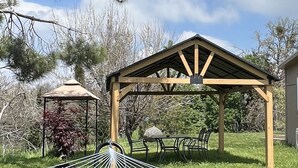 A hammock, a gazebo, and a picnic table in a grassy outdoor area.