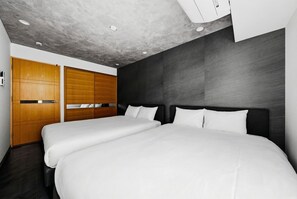 A room with two beds, wooden wardrobe, and a grey textured ceiling. - LUXURY (Sapporo)