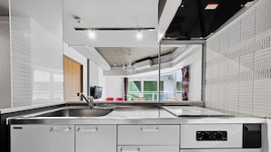 Een moderne keuken met een spoelbak van roestvrij staal, een inbouwoven en een kroonluchter.