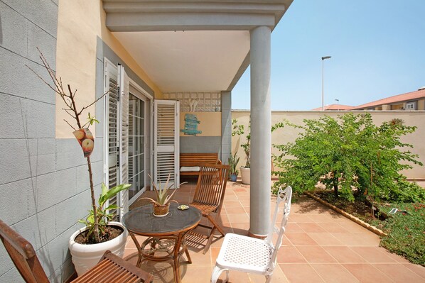 A covered patio with a table, chairs, and a potted plant.