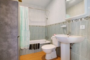 A bathroom with a bathtub, toilet, and sink.
