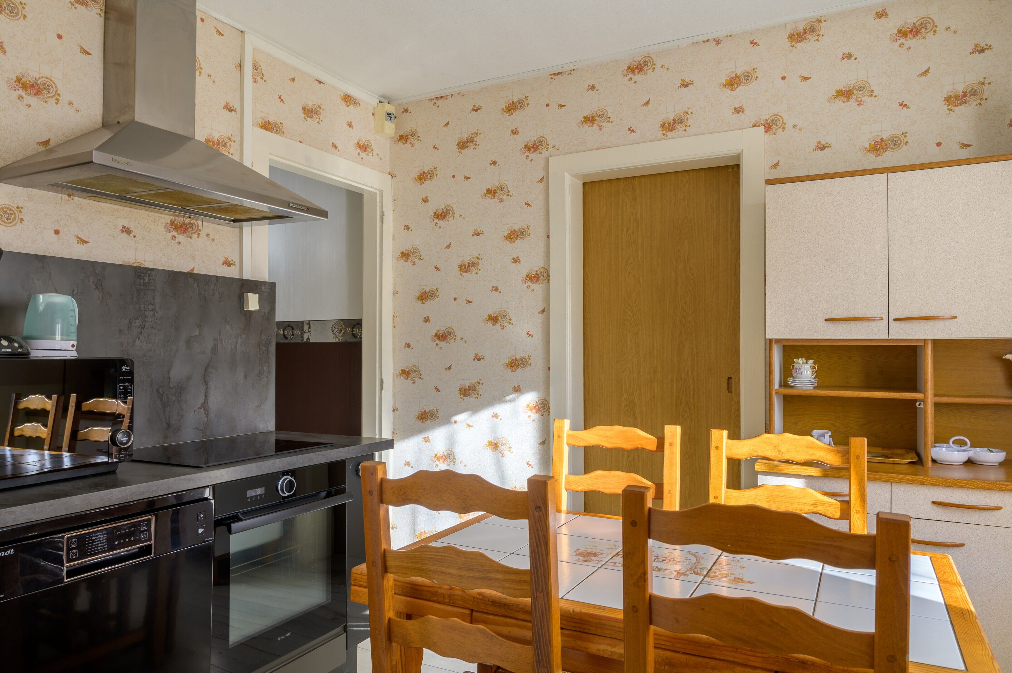 A kitchen with a stove, oven, and a wooden dining table with chairs.