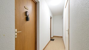 Un pasillo con una puerta de madera, un teclado electrónico y una pequeña placa.