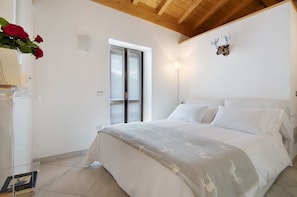 Un dormitorio con cama, ventana, lámpara de pared y cabeza de venado decorativa.