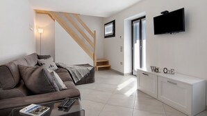 Una sala de estar moderna con un sofá, una mesa de centro, un televisor y una escalera.