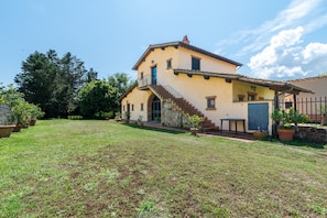 A two-story house with a staircase leading to the entrance, surrounded by a well-maintained lawn and potted plants. - Farmhouse "Officina" with Shared Pool, Private Terrace & Wi-Fi (Laterina)