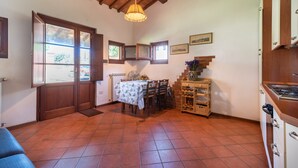 A room with a dining table, chairs, a wooden cabinet, a fan, and a window with a view. - Farmhouse "Officina" with Shared Pool, Private Terrace & Wi-Fi (Laterina)