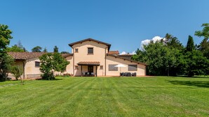 A two-story house with a patio, a lawn, and trees. - Farmhouse "Officina" with Shared Pool, Private Terrace & Wi-Fi (Laterina)