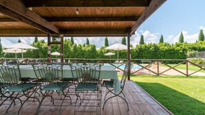 An outdoor covered patio with a pool, green chairs, and umbrellas. - Farmhouse "Officina" with Shared Pool, Private Terrace & Wi-Fi (Laterina)