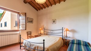 A bedroom with a bed, two bedside tables, a window, and a chair. - Farmhouse "Officina" with Shared Pool, Private Terrace & Wi-Fi (Laterina)